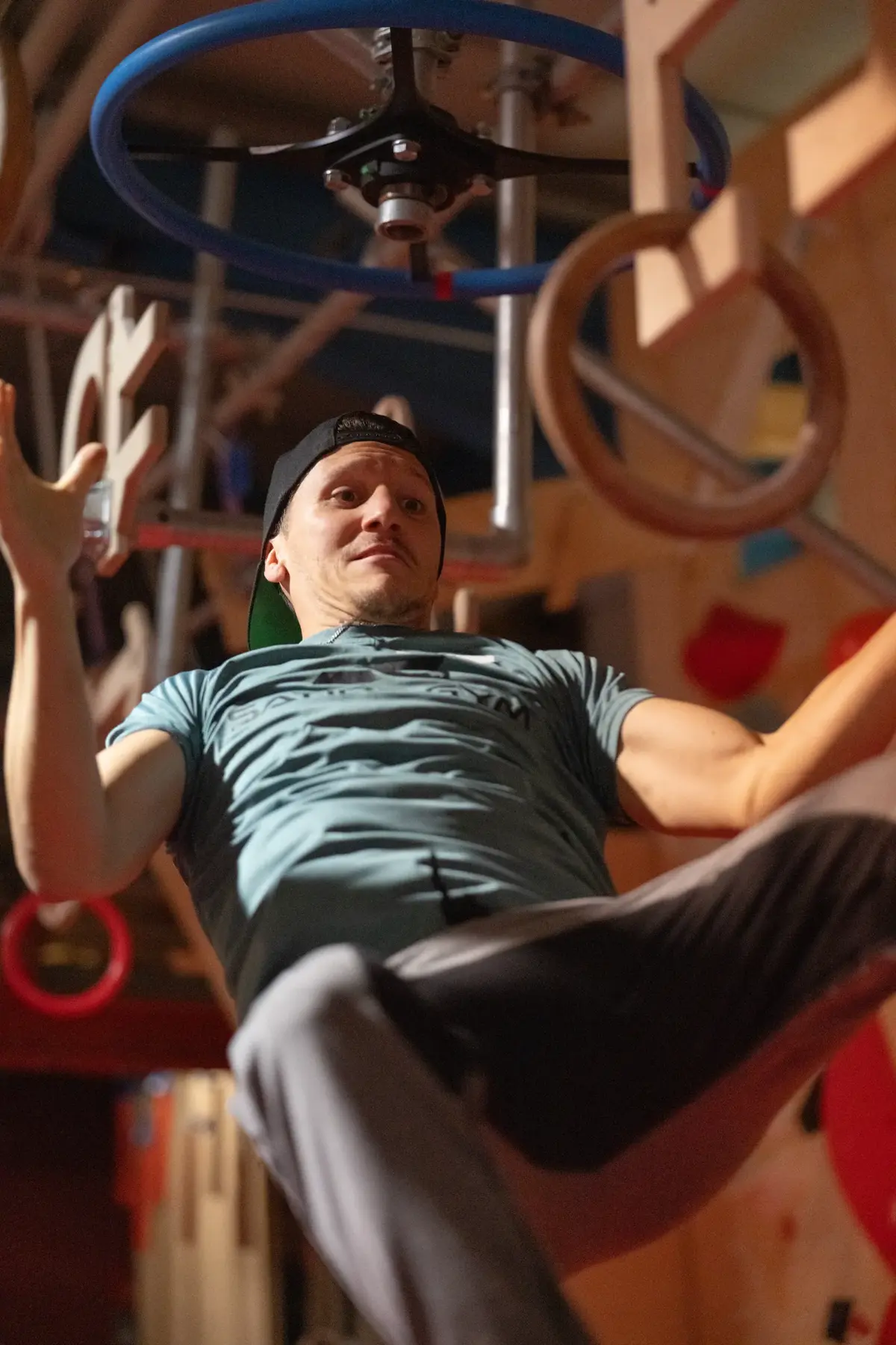 Athlet schwingt sich an Ringen durch den Ninja-Warrior-Parcours
