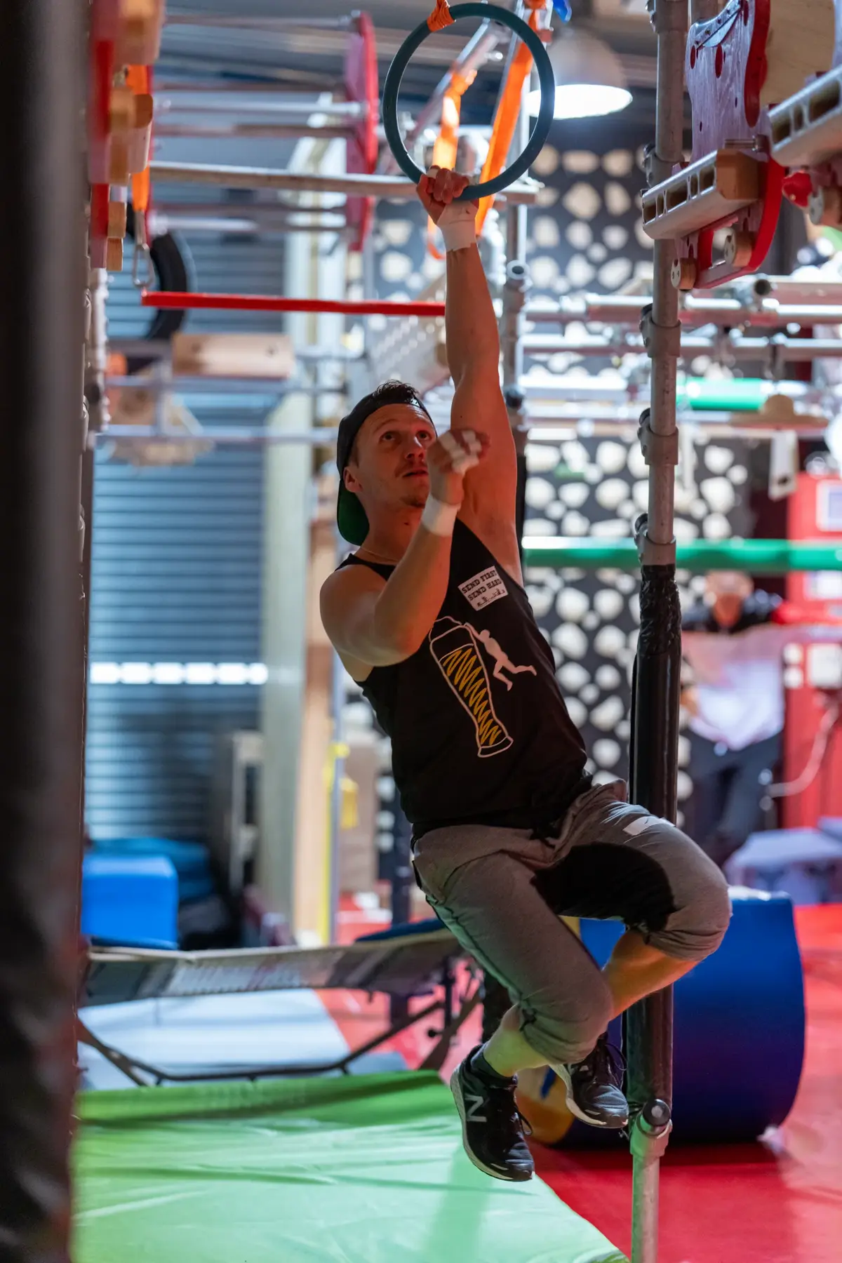 Athlet hangelt sich in der Halle an einem Ring durch den Parcours